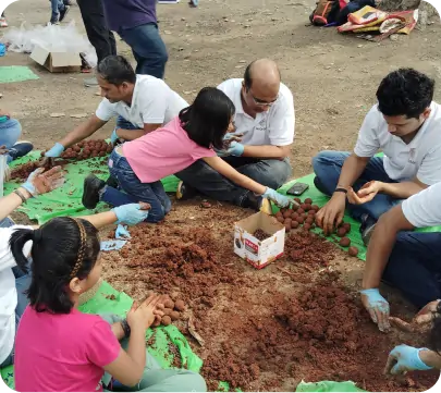 Volunteers including children participating in seedball preparation activity